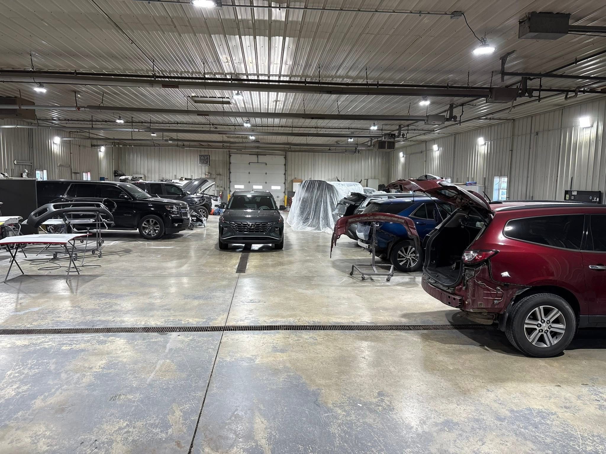 Multiple vehicles being serviced inside the Adams County Collision & Repair shop